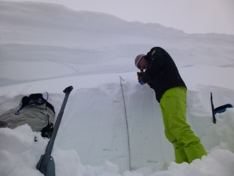 Snowpit in crown of avalanche with cornice above